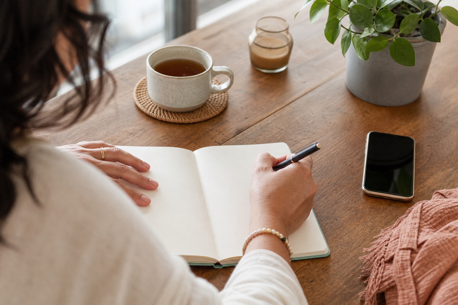Woman writing in a blank tracker notebook for perimenopause irregular periods