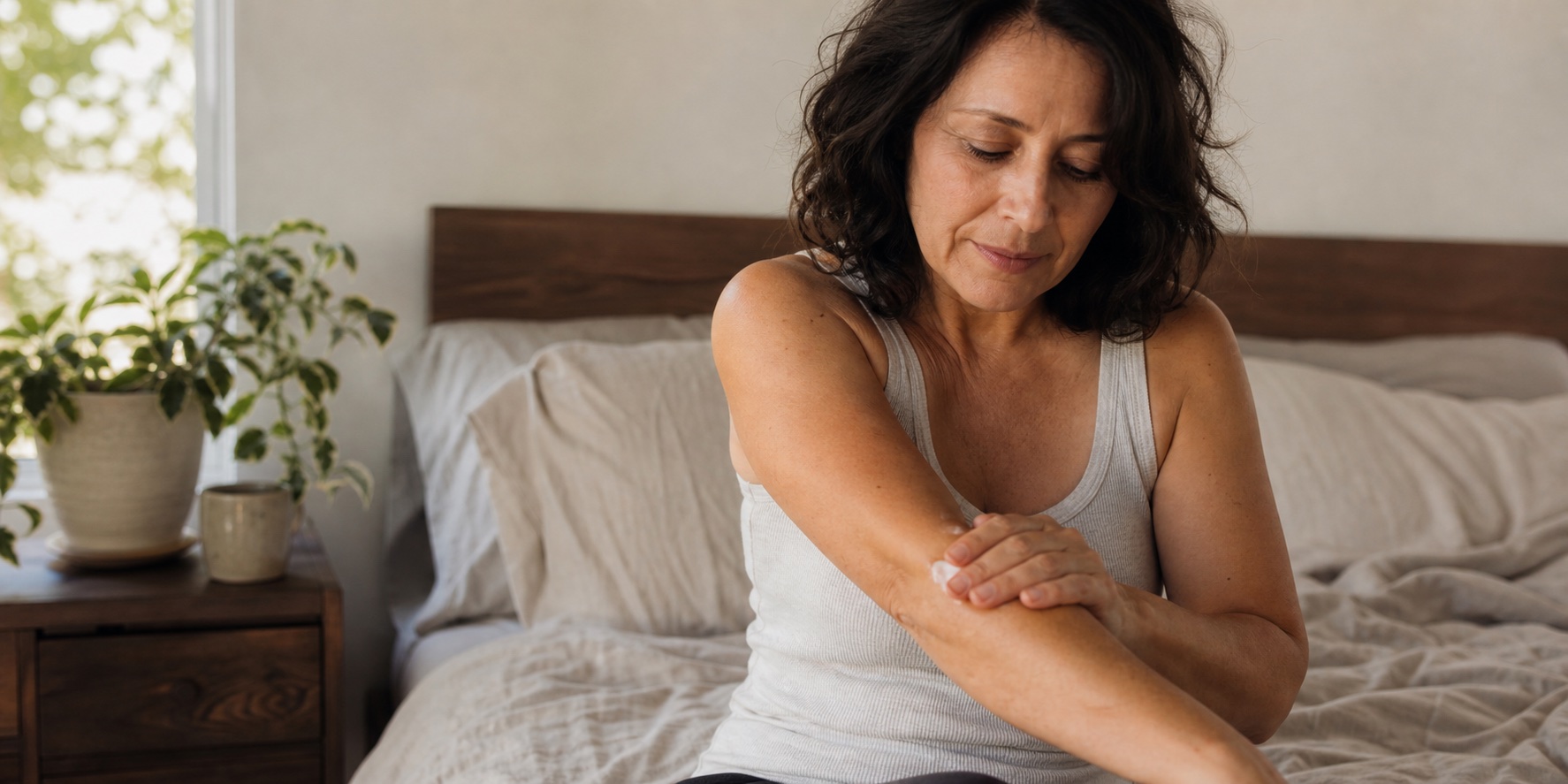 Woman in her 40s moisturizing her forearm while thinking about perimenopause itchy skin
